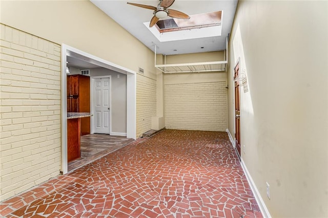 interior space with visible vents, brick wall, brick floor, and baseboards