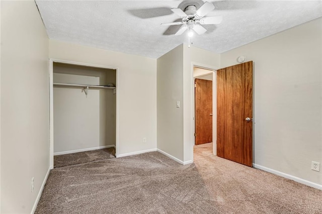 unfurnished bedroom featuring carpet floors, a closet, baseboards, a textured ceiling, and a ceiling fan