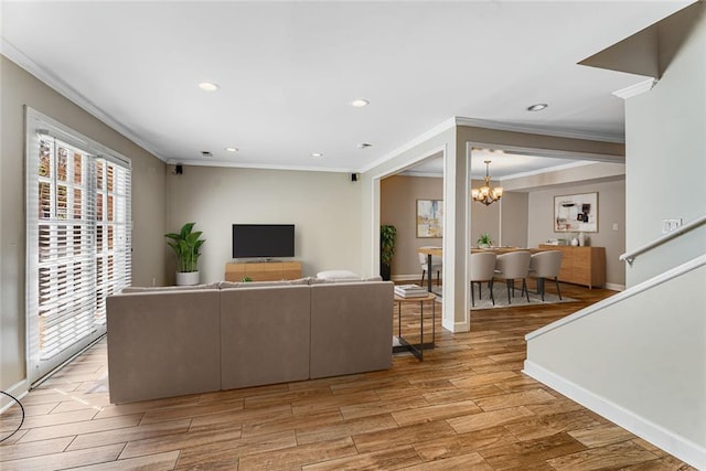 living room featuring crown molding, light wood-style flooring, plenty of natural light, and a chandelier