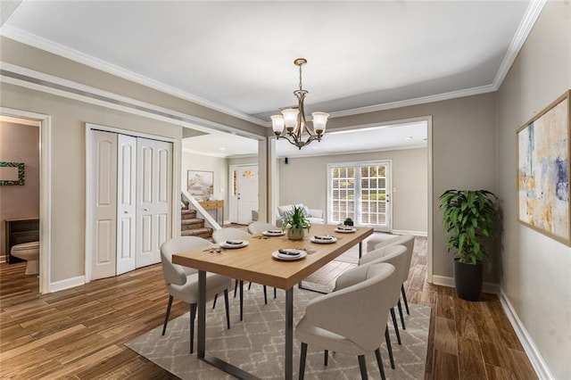 dining space with crown molding, wood finished floors, baseboards, and a chandelier