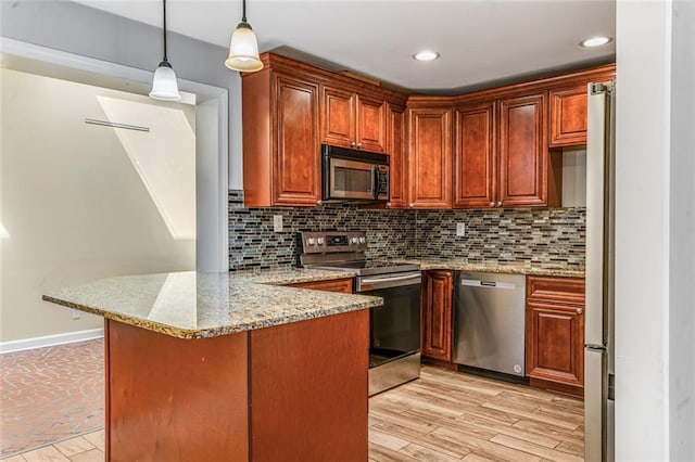 kitchen with stainless steel appliances, decorative light fixtures, baseboards, decorative backsplash, and a peninsula
