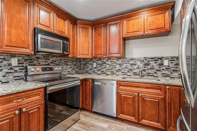 kitchen with tasteful backsplash, brown cabinets, stainless steel appliances, and a sink