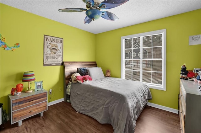 bedroom with a textured ceiling, baseboards, and wood finished floors