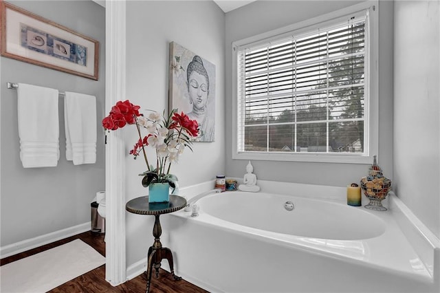 bathroom featuring a garden tub, baseboards, and wood finished floors