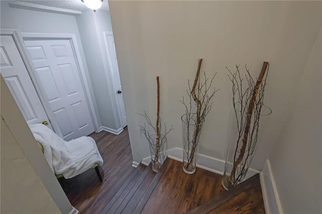 corridor with dark wood-style floors and baseboards