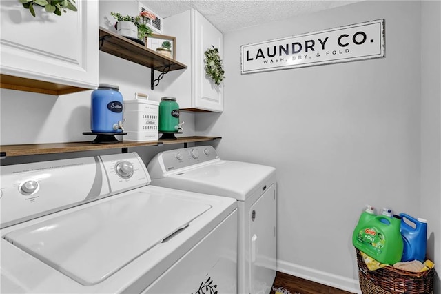 clothes washing area with cabinet space, baseboards, wood finished floors, washing machine and clothes dryer, and a textured ceiling