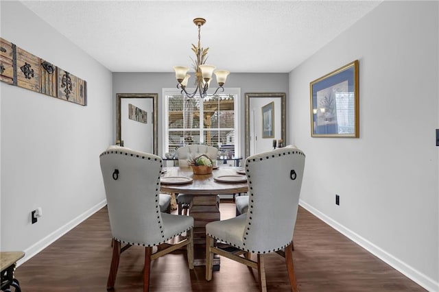 dining room featuring a notable chandelier, a textured ceiling, baseboards, and wood finished floors