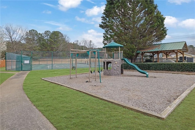 community jungle gym featuring fence and a lawn