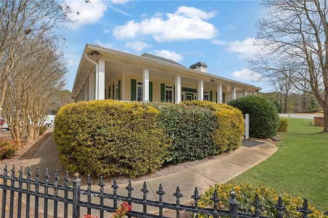 view of side of home featuring a yard, a fenced front yard, and a chimney