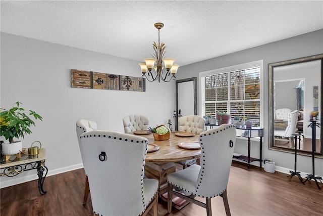 dining space featuring an inviting chandelier, a textured ceiling, baseboards, and wood finished floors