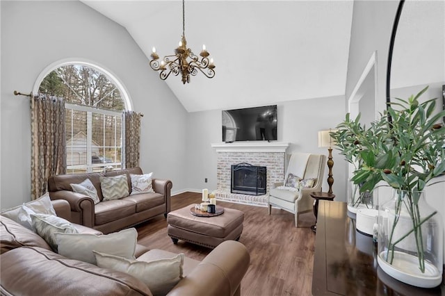 living room with an inviting chandelier, a brick fireplace, wood finished floors, high vaulted ceiling, and baseboards