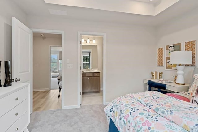 bedroom with connected bathroom and light colored carpet