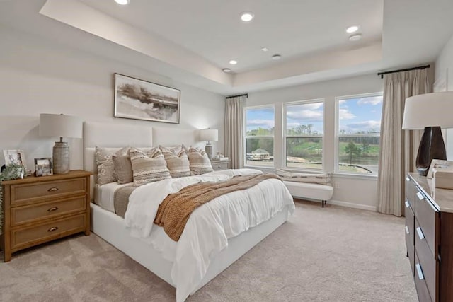 bedroom featuring a raised ceiling and light colored carpet