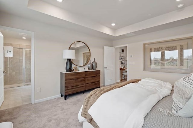 bedroom featuring a tray ceiling, ensuite bath, and light carpet