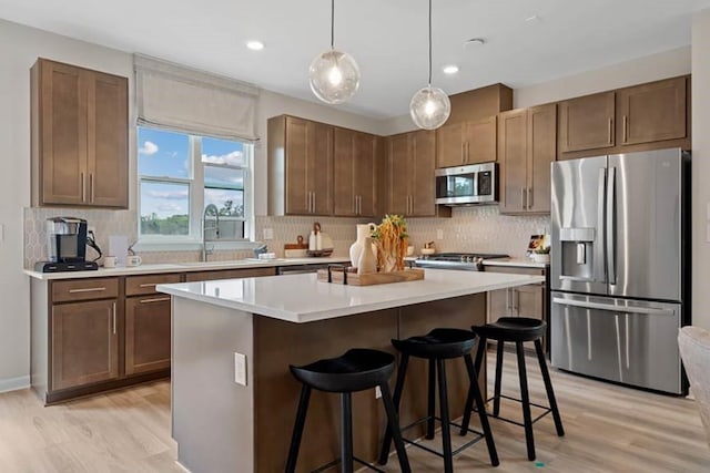 kitchen featuring a breakfast bar, stainless steel appliances, sink, a kitchen island, and hanging light fixtures