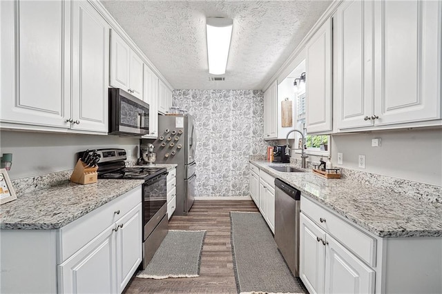 119 Ashley Way, Jefferson, GA 30549 - kitchen featuring appliances with stainless steel finishes, a sink, wood finished floors, white cabinets, and a textured ceiling