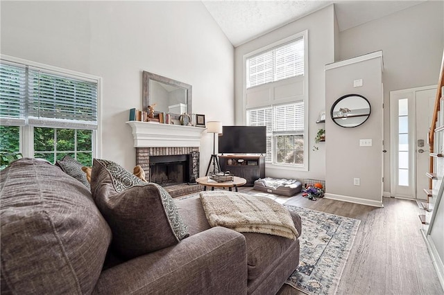 119 Ashley Way, Jefferson, GA 30549 - living room featuring high vaulted ceiling, plenty of natural light, wood finished floors, a brick fireplace, and baseboards