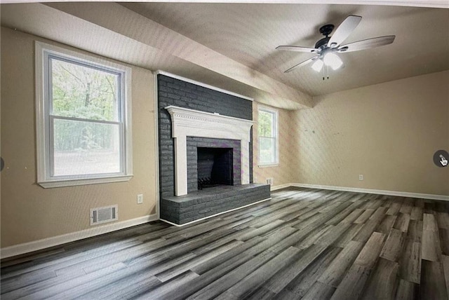 unfurnished living room with a brick fireplace, a healthy amount of sunlight, and dark hardwood / wood-style flooring