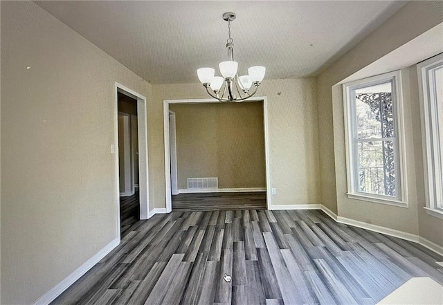 unfurnished dining area with a notable chandelier and dark wood-type flooring