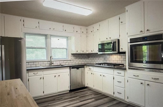 kitchen with dark wood-type flooring, sink, white cabinetry, appliances with stainless steel finishes, and tasteful backsplash