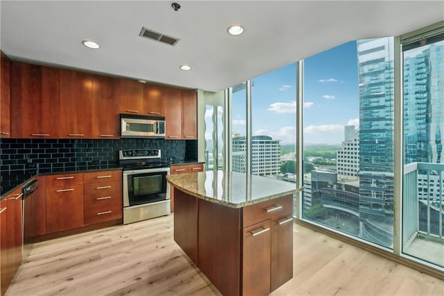 kitchen featuring stainless steel appliances, light wood-type flooring, dark stone countertops, decorative backsplash, and a view of city