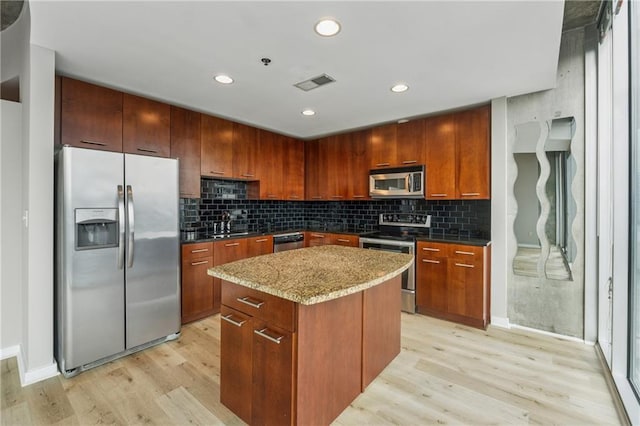 kitchen featuring stainless steel appliances, light wood-style floors, a center island, decorative backsplash, and recessed lighting