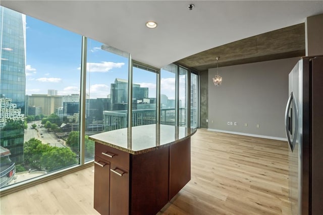 kitchen featuring freestanding refrigerator, light wood-style floors, a chandelier, a view of city, and floor to ceiling windows