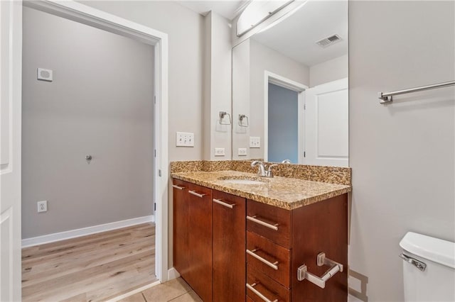 bathroom featuring toilet, vanity, and baseboards
