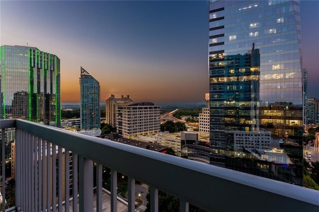 balcony at dusk featuring a view of city