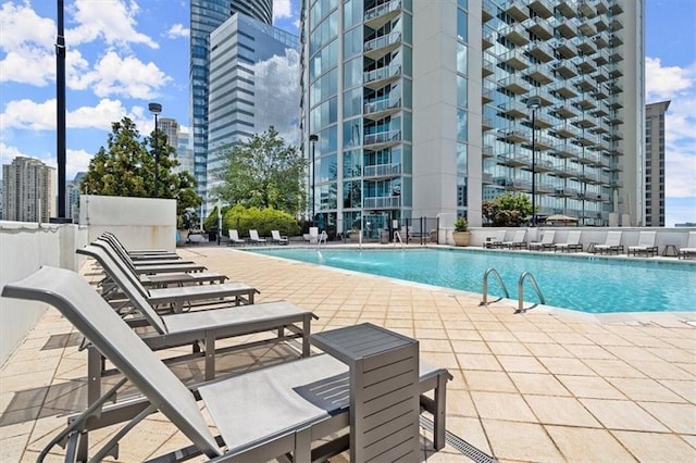 community pool with a patio area and a view of city