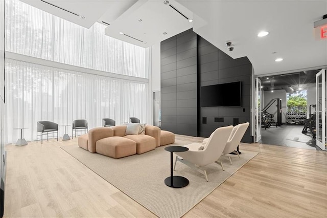 living room featuring wood finished floors, a towering ceiling, and recessed lighting