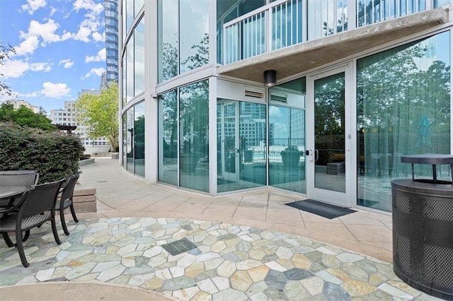 view of exterior entry featuring a patio area and a balcony