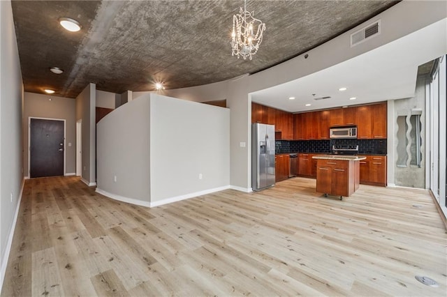 kitchen with appliances with stainless steel finishes, open floor plan, light wood-style floors, decorative backsplash, and a center island