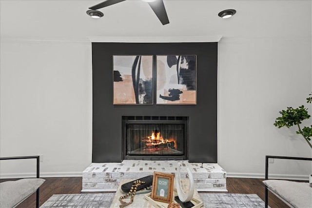 details with ceiling fan, a fireplace, wood-type flooring, and ornamental molding