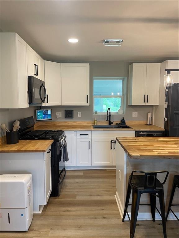 433 Spring Place Reseca Rd, Resaca, GA 30735 - kitchen with butcher block counters, black appliances, a sink, a kitchen bar, and white cabinets