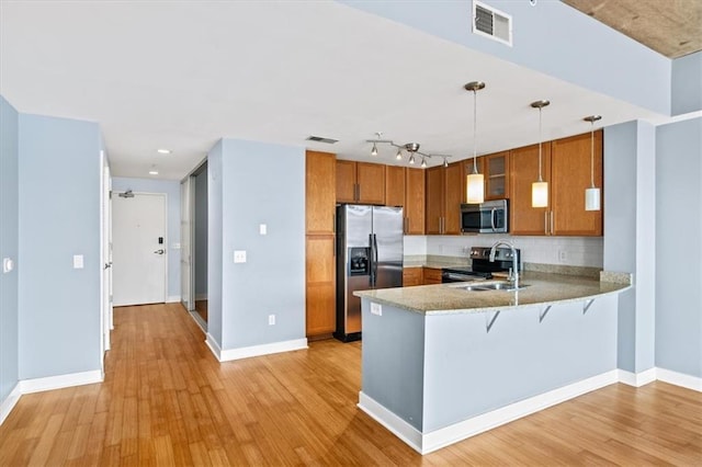 kitchen featuring sink, stainless steel appliances, decorative light fixtures, kitchen peninsula, and light wood-type flooring