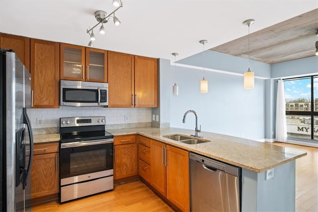 kitchen featuring hanging light fixtures, appliances with stainless steel finishes, sink, and kitchen peninsula