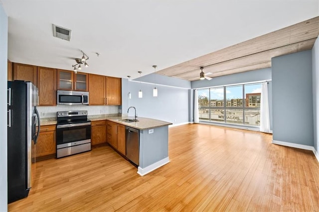 kitchen featuring sink, tasteful backsplash, hanging light fixtures, appliances with stainless steel finishes, and kitchen peninsula