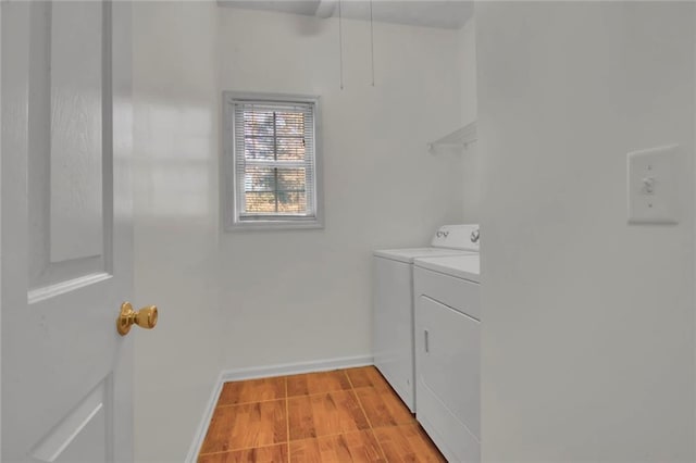 clothes washing area featuring laundry area, baseboards, light wood finished floors, and washer and clothes dryer