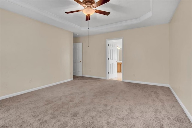 spare room with crown molding, ceiling fan, baseboards, a tray ceiling, and carpet flooring