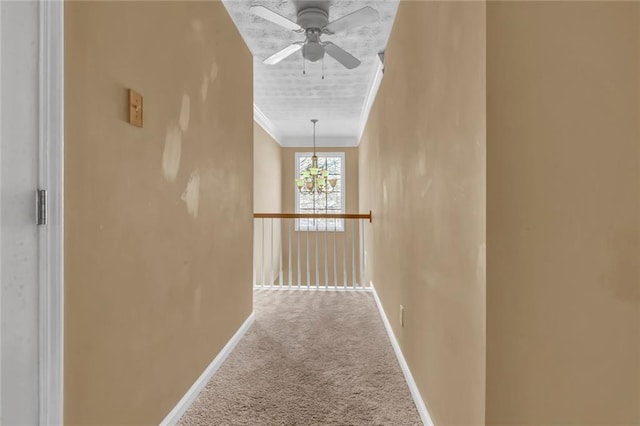 corridor with baseboards, carpet, an inviting chandelier, and crown molding