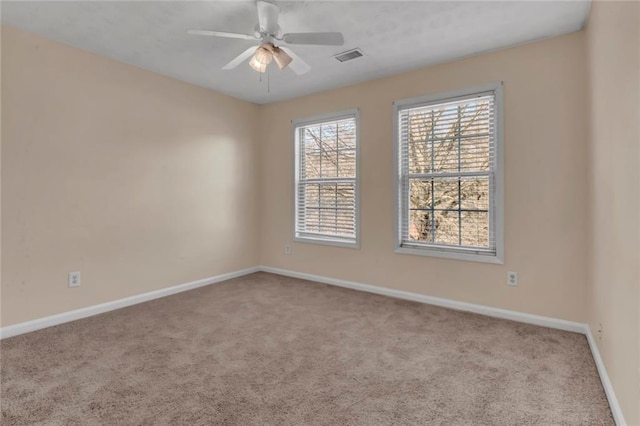 carpeted empty room with visible vents, baseboards, and ceiling fan