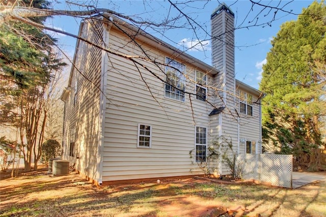 view of side of home featuring central air condition unit and a chimney