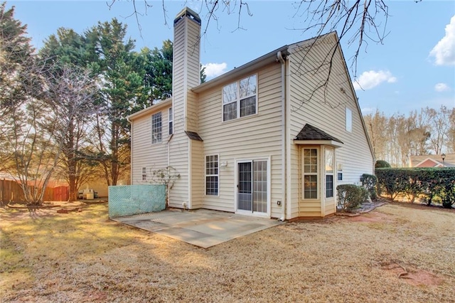 back of house featuring fence, a lawn, a chimney, and a patio area