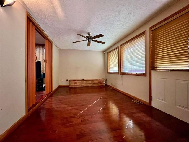 spare room featuring dark wood-type flooring, ceiling fan, and a textured ceiling