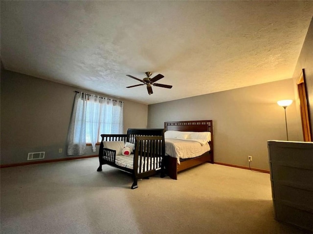 carpeted bedroom with ceiling fan and a textured ceiling