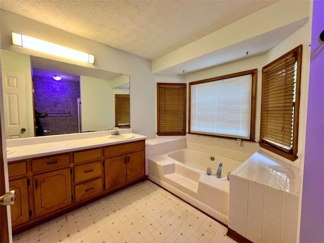 bathroom featuring a tub to relax in, vanity, and a textured ceiling