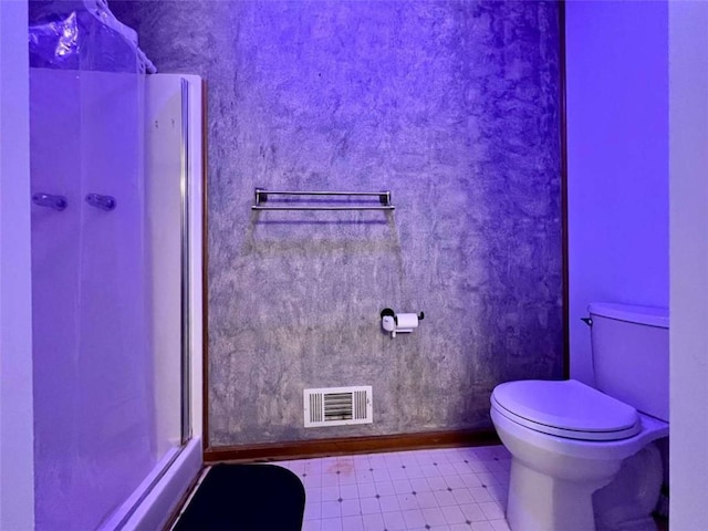 bathroom with a shower with shower door, tile patterned floors, and toilet