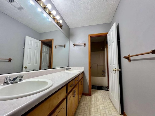 bathroom featuring vanity, a textured ceiling, and bathing tub / shower combination