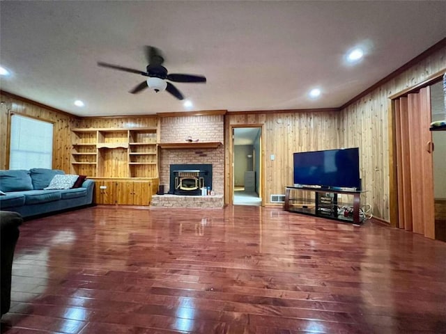 living room featuring ornamental molding, wood walls, ceiling fan, and dark hardwood / wood-style floors